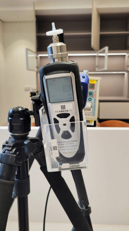 腳架上的VOC氣體偵測器螢幕顯示83 ppb，背景為櫃門打開的客廳空間